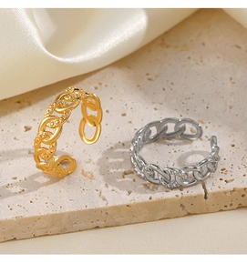 Detail of 18K gold and silver chain link rings on a stone base with silk fabric