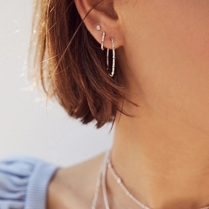 Detail view of s925 sterling silver square huggie earrings worn on model ear