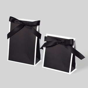 Minimalist black gift bags with white trim and large silk bow tie in two sizes