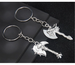 Detailed view of silver Viking double axe and dragon head keychains on textured background