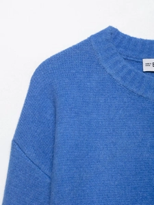 Detail view of bright blue knit sweater showing soft wool texture and round neckline finish