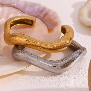 Detail of gold and silver irregular liquid wave bangles with water droplets on shell