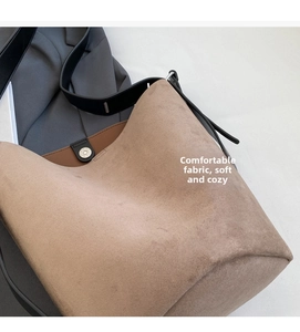 Detail of soft brown faux suede bucket bag with magnetic silver buckle and black strap