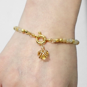 Beaded natural stone bracelet with gold heart pendant on model wrist for women