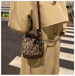 Street style view of leopard print bucket bag with dark brown leather trim and gold hardware