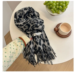 Detailed close-up of leopard print cashmere scarf showing the material tag and tassels
