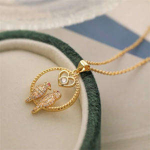 Gold bird heart pendant necklace with shimmering cubic zirconia stones on jewelry box