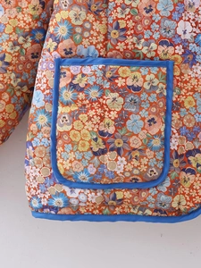 Détail de veste matelassée Y2K à fleurs montrant la poche bordée de bleu et l'imprimé