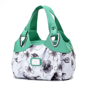 Close-up of white fabric floral print and green faux leather handles on handbag