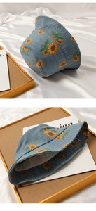 Detail of light blue denim bucket hat featuring vibrant sunflower print and soft texture