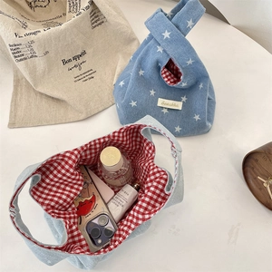 Detailed view of the red plaid lining and white star print on a denim wrist bag