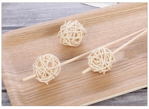 Dettaglio di palline di rattan da 3 cm con bastoncini diffusori su vassoio in legno