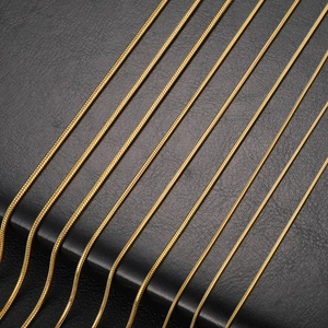 Minimalist gold-plated stainless steel snake bone chain necklaces on black leather background