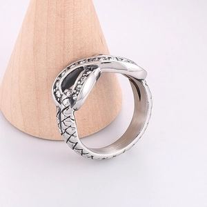 Detail of silver snake-textured ring with pavé stones on a wooden jewelry display stand