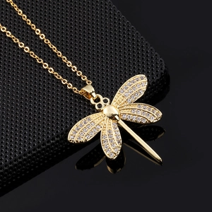 Detail of dragonfly pendant with white crystals and black gemstones on gold chain
