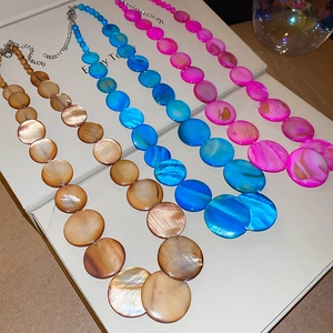 Detailed view of colorful shell necklaces with round discs and lobster clasp closure
