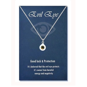 Close-up of silver evil eye necklace with white pendant on blue presentation card