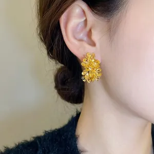 Golden 3D floral C-shaped stud earrings in a textured metallic blossom design