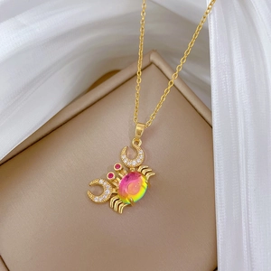 Macro shot of a golden crab pendant with rainbow gemstone and crystals in a jewelry box