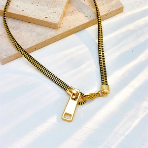Collana in stile punk con design a cerniera dorata su un supporto in pietra minimalista