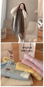 Detail of soft cashmere-feel scarves with fringed ends and macaron leather labels