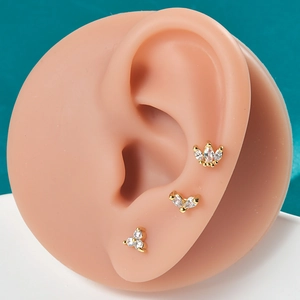 Macro shot of gold stainless steel stud earrings set with zircons on a silicone ear model