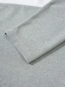 Détail de la texture en maille gaufrée grise et couture de manche du pull pour homme