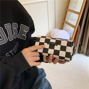 Detail of checkered canvas pencil case with black logo label and top zipper closure