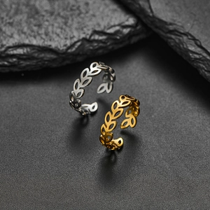 Adjustable stainless steel leaf rings in gold and silver set on a dark stone background