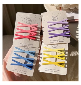 Close-up of candy-colored X-shaped matte hair clips on display cards in four gradient colors