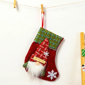 Detail of red Christmas stocking with green plaid cuff and HO HO HO embroidery on rope