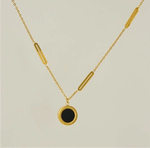Détail macro du collier asymétrique or 18k avec insert noir et gravures chiffres romains