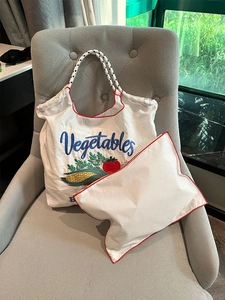 Macro shot of embroidered nylon bag showing a vegetable pattern and contrast piping
