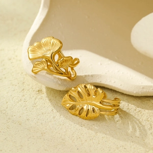 18K gold plated ginkgo and monstera leaf rings on a white ceramic display tray