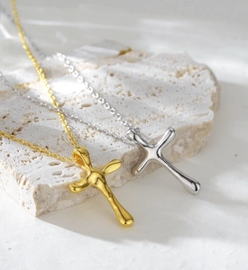 Detailed view of silver and gold irregular lava texture cross necklaces on stone