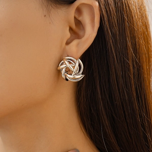 Close-up of geometric hollow flower whirlpool earring in silver metal finish on model