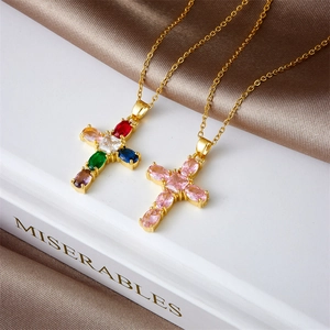 Elegant gold cross necklaces with colorful and pink zircons on a white vintage book