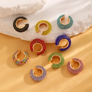 Macro detail of nine colorful rhinestone C-shaped ear cuffs on gold metal base