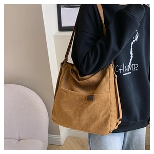 Détail du sac cabas en velours côtelé marron montrant le tissu et l'étiquette mode