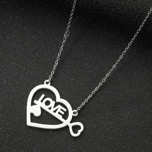 Dettaglio ravvicinato di un ciondolo a cuore argento con incisione LOVE su sfondo scuro