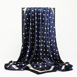 Sciarpa di seta blu a pois bianchi con bordo bianco su supporto da esposizione