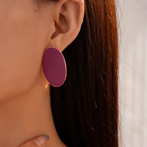 Close-up of vintage purple matte oval earrings with gold trim worn by a model
