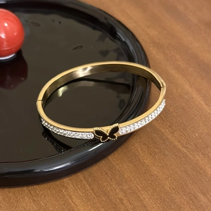 Elegant gold-tone bangle with white zircon rows and a black butterfly center ornament