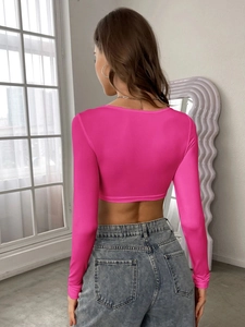 Rear view of a hot pink long sleeve knit crop top paired with gray denim jeans