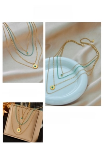 Detail of layered gold chain necklace with turquoise beads and textured round pendants