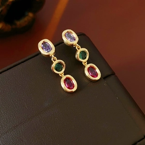 Detail von Vintage-Goldohrringen mit violetten, grünen und roten ovalen Edelsteinen