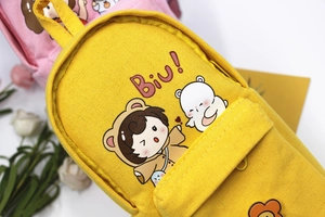 Close-up of yellow canvas pencil case featuring a cute mini backpack design with a bear print