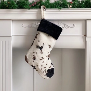 Detail of 20-inch cow print Christmas stocking hanging on a white festive fireplace