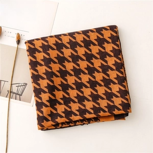 Detail of soft houndstooth pattern scarf in orange and brown with magazine prop