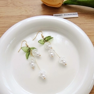 Detail of long lily of the valley earrings with green leaves and pearl accents